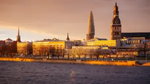 Rīgas panorāma ar Doma baznīcas torni un Daugavu zelta saulrietā.