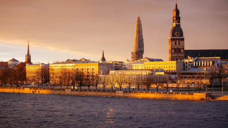 Rīgas panorāma ar Doma baznīcas torni un Daugavu zelta saulrietā.