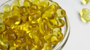 Dzeltenas D vitamīna kapsulas stikla traukā uz gaišas un tīras virsmas.