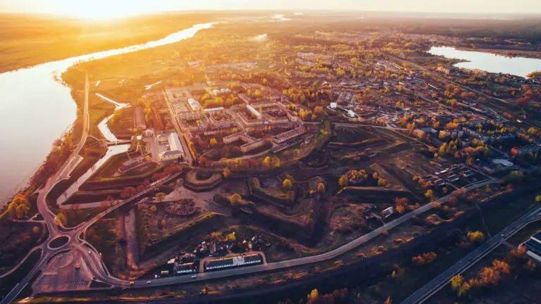 Panorāmas skats uz Daugavpili saulrieta laikā ar Daugavas upi un pilsētas apbūvi.