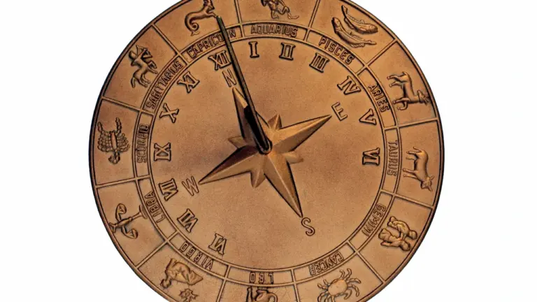 Bronzas zodiaka aplis ar iegravētām zvaigznāju zīmēm uz pulksteņa ciparnīcas fona.