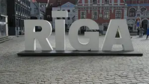 Liels, balts uzraksts RĪGA uz bruģēta laukuma Rīgas vēsturiskajā centrā.