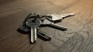 Saišķis ar vairākām atslēgām novietots uz koka galda virsmas tuvplānā.